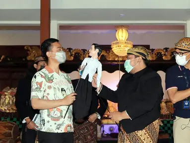 Menteri Parekraf Sandiaga Uno (kanan) dan Walikota Solo Gibran Raka Bumi (kiri) menerima wayang di Solo, Jawa Tengah, Sabtu (09/10/2021). Pada kunjungan ke Solo, Sandiaga sepakat untuk mengembangkan kesenian dan ekonomi kreatif untuk peningkatan ekonomi bagi masyarakat. (Liputan6.com/HO/Parekraf)