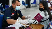 Salah satu petugas Pusat Vaksinasi Garut tengah melakukan pemeriksaan kesehatan kepada warga yang akan melakukan vaksinasi Covid-19.  (Liputan6.com/Jayadi Supriadin)