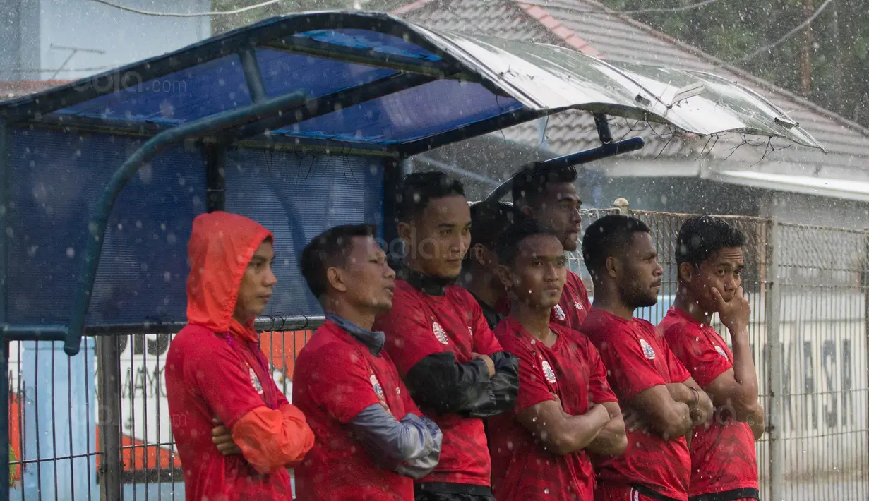Para pemain Persija Jakarta berteduh dari hujan saat latihan di Lapangan Sutasoma, Jakarta, Rabu (31/1/2018). Latihan ini merupakan persiapan jelang babak delapan besar Piala Presiden. (Bola.com/Asprilla Dwi Adha)