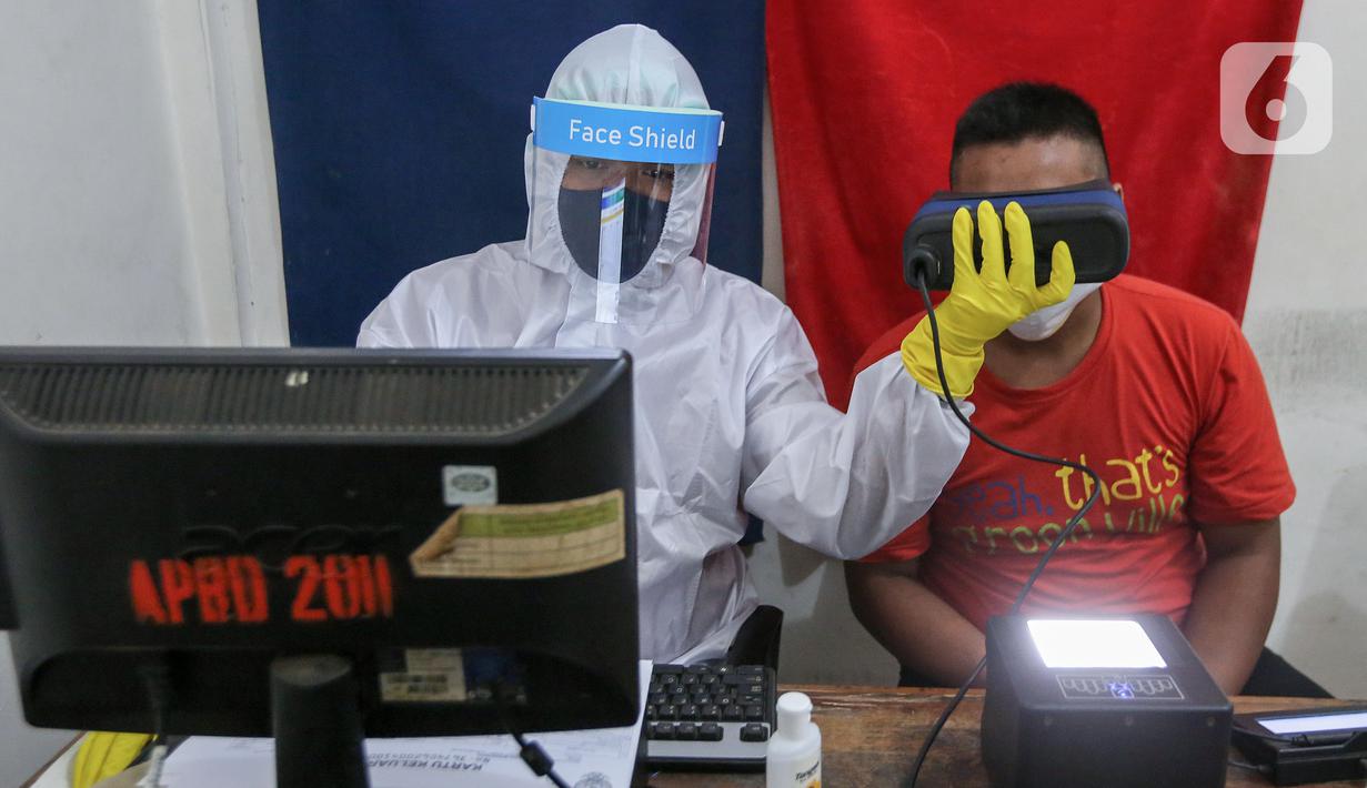 Petugas Dukcapil lengkap dengan APD merekam untuk KTP Elektronik di Kecamatan Pamulang, Tangerang Selatan, Senin (15/6/2020). Dukcapil Tangsel membuka layanan rekaman E-KTP menjelang Pilkada dengan menerapkan ketentuan New Normal guna mencegah penyebaran Virus Covid-19. (Liputan6.com/Fery Pradolo)