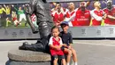 Dua anak Irfan dan Jennifer, Kenji dan Kiyoki berpose di depan patung salah satu legenda sepak bola Arsenal, Thierry Henry. [Instagram/ibachdim]
