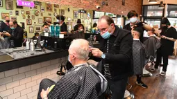 Para pria memotong rambut di barber shop di Melbourne, Australia, Senin (19/10/2020). Warga Kota Melbourne, pada Senin (19/10), akhirnya bisa bernafas lega saat sejumlah pembatasan dilonggarkan setelah menjalani lockdown tahap keempat yang ketat selama sekitar 100 hari. (William WEST/AFP)