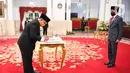Kepala Badan Pelindungan Pekerja Migran Indonesia (BP2MI) Benny Rhamdani menandatangani dokumen disaksikan Presiden Joko Widodo  usai pelantikan di Istana Negara, Jakarta, Rabu (15/4/2020). (Antarafoto/Hafidz Mubarak/Pool)