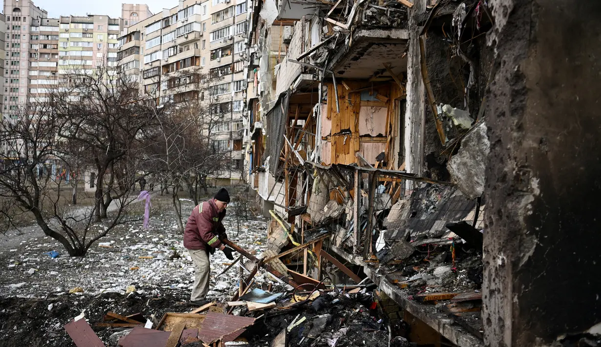 Seorang pria membersihkan puing-puing setelah peluru militer Rusia menghantam di sebuah bangunan tempat tinggal di Koshytsa Street, pinggiran ibukota Ukraina, Kiev (25/2/2022). Pasukan Rusia mencapai pinggiran Kyiv pada hari Jumat (24/2). (AFP/Daniel Leal)