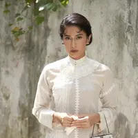 Dian Sastrowardoyo tampil dengan kebaya modern warna putih model halter neck yang memiliki detail renda. (@therealdisastr)