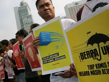 Peserta aksi memegang poster saat aksi peringati hari Hak Asasi Manusia (HAM) 2015 di Bundaran HI, Jakarta, Kamis (10/12/2015). Aksi untuk memperingati Hari HAM Internasional yang jatuh setiap tanggal 10 Desember. (Liputan6.com/Faizal Fanani)