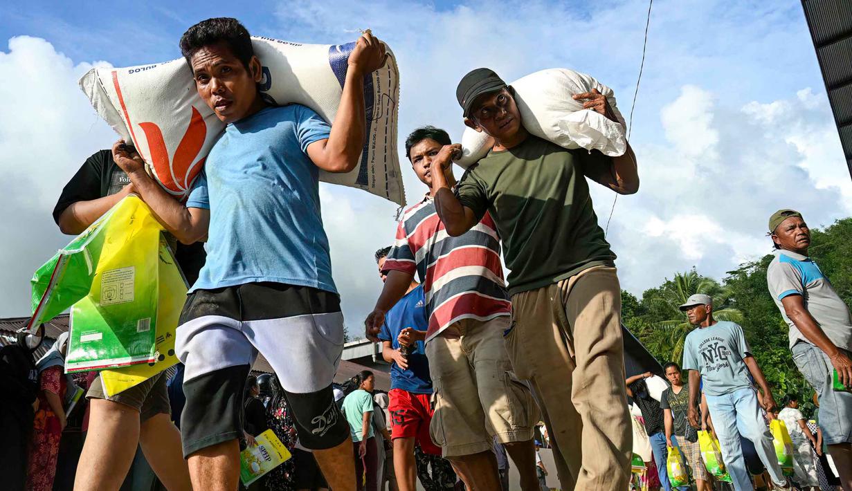Saat itu puluhan warga yang menjadi korban banjir bandang dan tanah longsor menyerbu bangunan tersebut dan menjarah bahan pokok yang tersimpan di dalam gudang. Tampak dalam foto, warga desa menerima bahan pangan pokok yang didistribusikan di tengah upaya bantuan dari gudang beras pemerintah di Sarudik, Tapanuli Tengah, Provinsi Sumatra Utara, pada Rabu 3 Desember 2025. (YT Hariono/AFP)