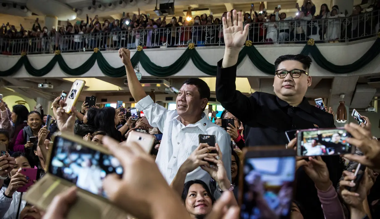 Peniru Presiden Filipina Rodrigo Duterte, Cresencio Extreme (tengah) dan peniru pemimpin Korea Utara Kim Jong Un, Howard X melambaikan tangan ketika menghadiri kebaktian gereja di pusat Hong Kong pada 3 Februari 2019. (ISAAC LAWRENCE/AFP)