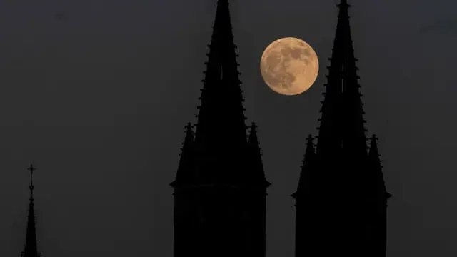 Bulan purnama terbit di belakang Basilika Santo Petrus dan Santo Paulus, bagian dari Kastil Vysehrad, di Praha, Republik Ceko, pada hari Selasa 25 Mei 2021 (Michal Cizek / AFP / Getty)