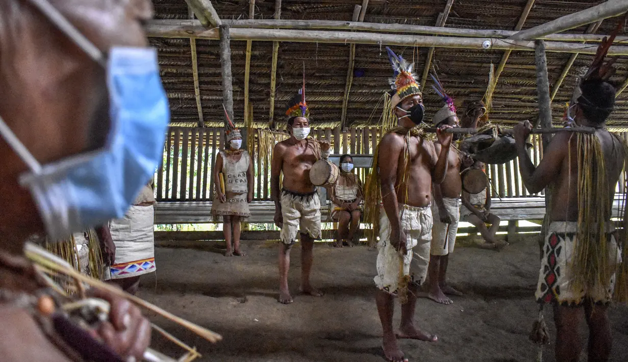 Suku Tikuna berpose mengenakan masker di tengah kekhawatiran virus corona Covid-19 di Leticia, Departemen Amazonas, Kolombia pada 8 Juni 2020. Kasus virus corona ini meningkatkan kekhawatiran akan resiko penyebaran ke masyarakat adat yang rentan dan berada di pedalaman. (Tatiana de NEVO/AFP)