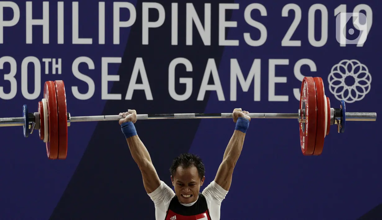 Lifter putra Indonesia, Suratman melakukan angkatan saat SEA Games 2019 cabang angkat besi nomor 55 kg di Stadion Rizal Memorial, Manila, Minggu (1/12/2019). Dirinya meraih perak dengan total angkatan 250 kg. (Bola.com/M Iqbal Ichsan)