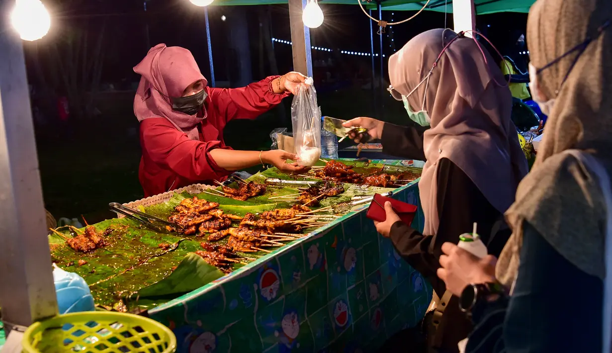 <p>Penjual melayani pembeli selama bulan suci Ramadhan di pasar malam di provinsi Narathiwat, Thailand selatan (21/4/2022). Penjual makanan jalanan mendirikan kios mereka untuk menjual makanan kepada umat Muslim untuk berbuka puasa. (AFP/Madaree Tohlala)</p>