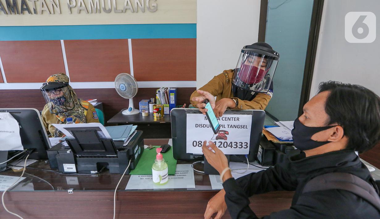 Petugas loket lengkap dengan masker dan face shield melayani warga saat proses pembuatan KTP Elektronik di Kecamatan Pamulang, Tangerang Selatan, Senin (15/6/2020). Dukcapil Tangsel membuka layanan rekaman E-KTP jelang Pilkada dengan menerapkan ketentuan New Normal. (Liputan6.com/Fery Pradolo)
