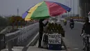 Seorang pedagang kelapa membenahi posisi payungnya di sore musim panas yang terik di Jammu, India, Kamis (19/5/2022). Banyak bagian barat laut dan tengah India terus mengalami kondisi gelombang panas. (AP Photo/Channi Anand)