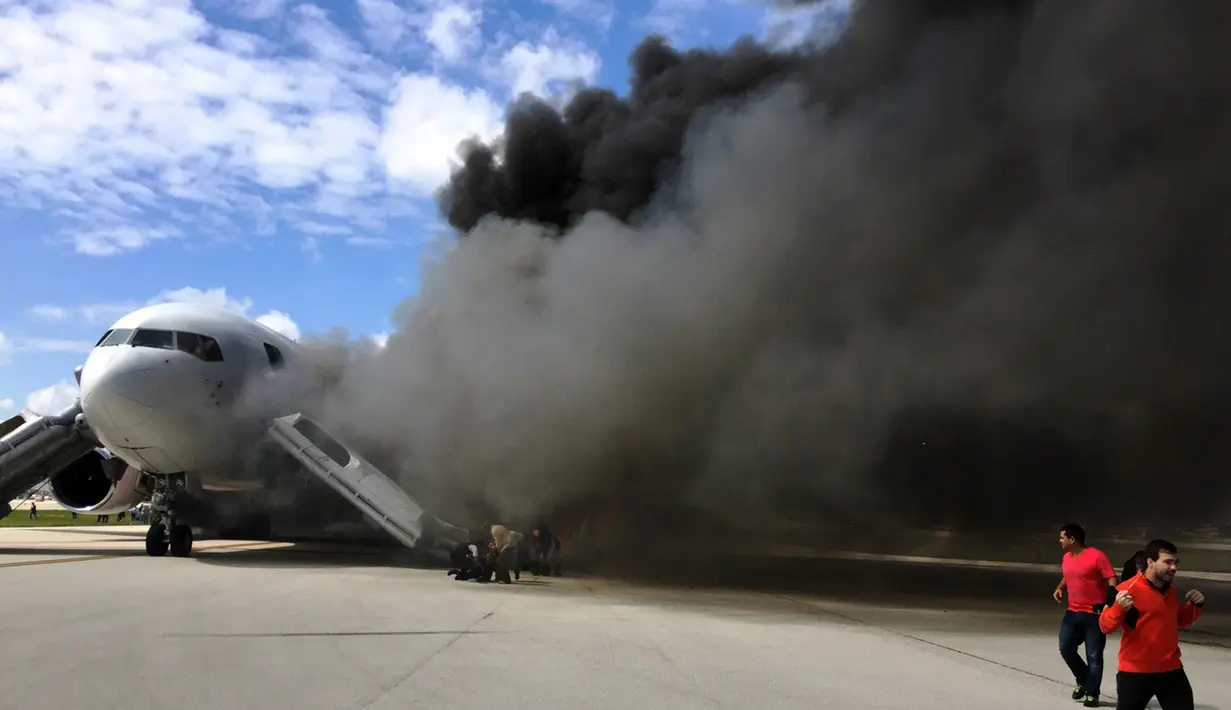 Penumpang dievakuasi dari pesawat Boeing 767-200ER milik maskapai Dynamic International Airways yang terbakar saat akan lepas landas di Bandara Fort Lauderdale, Florida, Kamis (29/10). 15 orang terluka akibat kejadian tersebut. (AFP PHOTO/Andres Gallego)