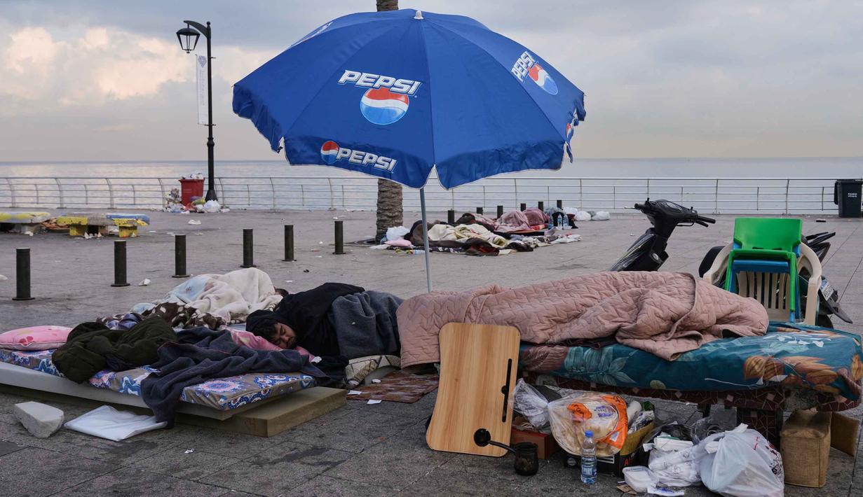 Situasi ini dipicu oleh peringatan serangan udara Israel terhadap infrastruktur yang diklaim sebagai milik Hizbullah di pinggiran selatan Beirut. Tampak dalam foto, para pengungsi yang melarikan diri dari serangan udara Israel di Dahiyeh, tidur di tepi Laut Mediterania di Beirut, Lebanon, Sabtu, 7 Maret 2026. (AP Photo/Bilal Hussein)