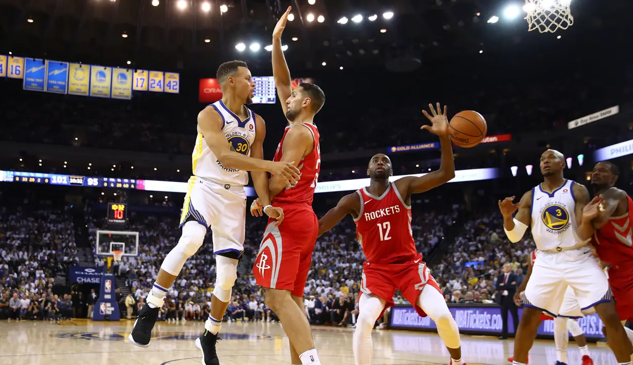 Stephen Curry #30 memberikan umpan kepada rekannya saat diadang para pebasket Houston Rockets pada laga perdana NBA 2017 di Oracle Arena, Oakland, (17/10/2017).  Rockets menang 122-121. Rockets menang 122-121. (Ezra Shaw/Getty Images/AFP)