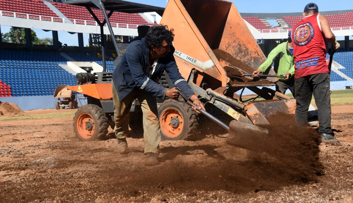 Seorang suporter menaburkan pasir saat menyelesaikan pembangunan stadion baru di Asuncion, Paraguay (22/6). Pembangunan stadion memiliki nilai proyek USD 15 juta atau Rp 199 miliar tersebut. (AFP Photo/Norberto Duarte)