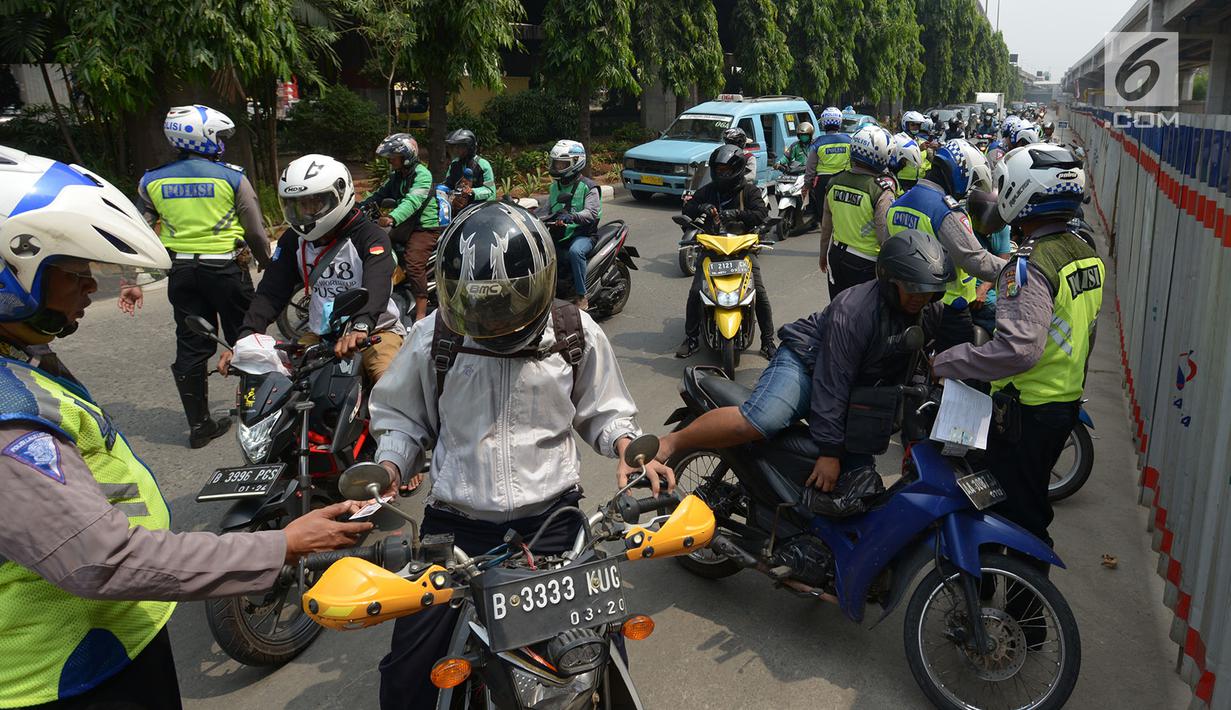 Polisi lalu lintas melakukan tilang terhadap pengendara motor saat razia Operasi Patuh Jaya 2019 di kawasan Kebon Nanas, Jakarta, Kamis (29/8/2019). Operasi ini diharapkan dapat meningkatkan kepatuhan dan ketertiban dalam berlalu lintas serta mengurangi angka kecelakaan. (merdeka.com/Imam Buhori)