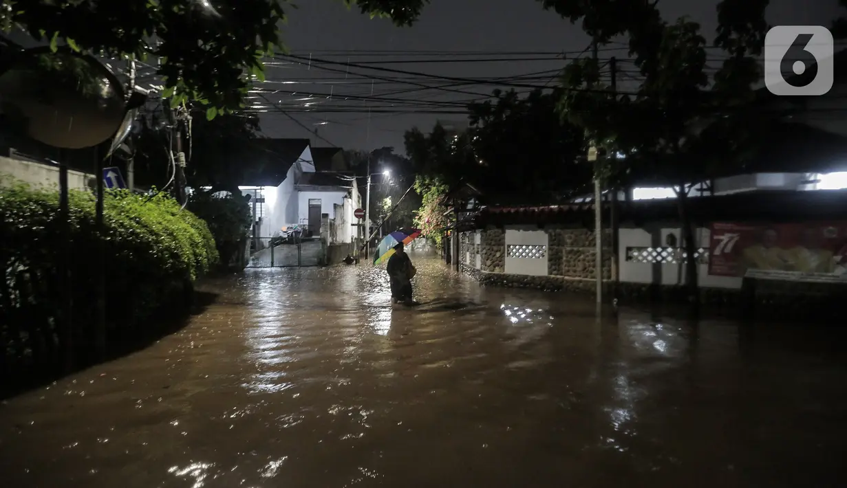 Warga melewati rumah yang tergenang banjir di jalan Bank, Jakarta Selatan, Selasa (4/10/2022). Hujan yang mengguyur wilayah Ibu Kota Jakarta mengakibatkan banjir menggenangi kawasan Kemang, Jakarta. (Liputan6.com/Johan Tallo)