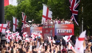 Para penggemar melambaikan tangan ke arah bus yang membawa para pemain dan staf selama perayaan kemenangan kepulangan timnas putri Inggris di The Mall di luar Istana Buckingham di London pada 29 Juli 2025 setelah tim tersebut memenangkan Euro 2025. (Adam Davy/POOL/AFP)