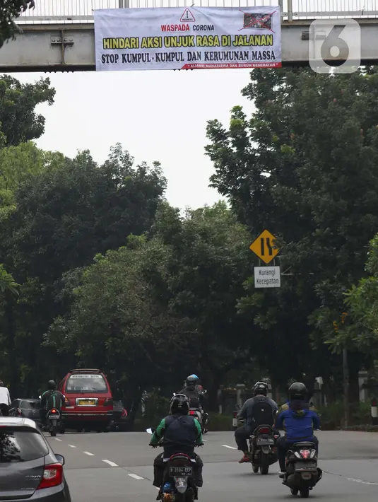Pengendara melintasi bawah Jembatan Penyeberangan Orang (JPO) di Jalan Raya Lenteng Agung, Jakarta, Selasa (17/3/2020). Sebuah spanduk berisi ajakan menghindari kerumunan dan kumpul-kumpul untuk mencegah penyebaran virus Corona COVID-19 terpasang di JPO teresebut. (Liputan6.com/Helmi Fithriansyah)