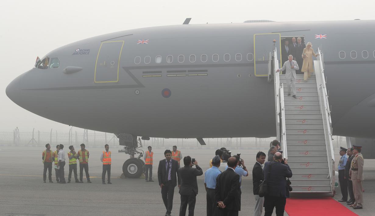 Pangeran Charles dan istrinya, Camilla menuruni tangga pesawat yang terselimuti kabut asap setibanya di New Delhi, India, Rabu (8/11). Pasangan dari Kerajaan Inggris itu akan berada di negara Anak Benua selama dua hari. (AP Photo/Manish Swarup)