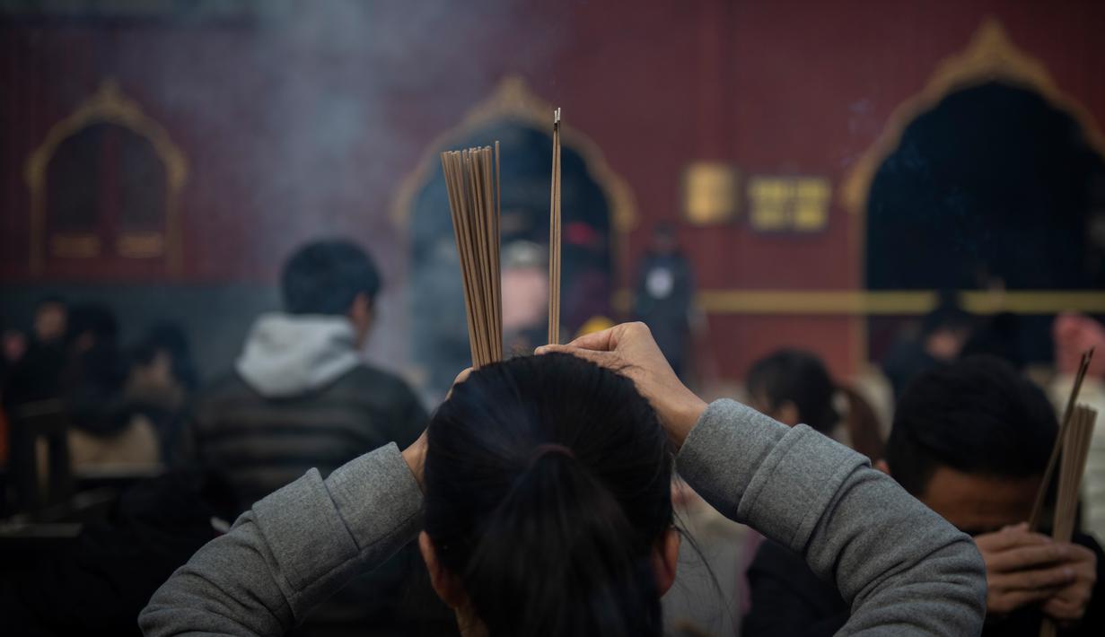 Seorang wanita berdoa untuk keberuntungan pada hari kelima Tahun Baru Imlek di Yonghegong, atau Kuil Lama di Beijing (9/2). Warga China di seluruh dunia menyambut Tahun Babi pada 5 Februari.  (AFP Photo/Nicolas Asfouri)