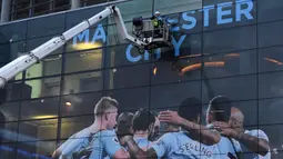 Pekerja memasang poster raksasa bergambar pemain Manchester City terpasang di Stadion Etihad, Manchester, Senin (17/4/2018). Persiapan ini dilakukan untuk merayakan pesta juara Manchester City meraih gelar Premier League. (AFP/Paul Ellis)