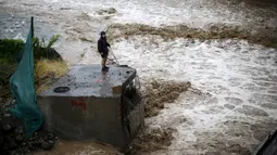 Seorang pria terlihat di sebelah sungai saat banjir melanda Ibu Kota Chile, Santiago, Minggu (17/4). Hujan lebat dan parah di Ibu Kota Chile selama akhir pekan lalu menyebabkan 1 orang tewas dan 7 orang masih dinyatakan hilang. (REUTERS/Ivan Alvarado)