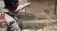 Kapolsek Tamalate, Kompol A. Arifuddin tampak menunjuk bagian tembokpembatas yang runtuh dan menimpa dua bocah bersaudara di Makassar hingga tewas (Liputan6.com/ Eka Hakim)