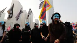 Demonstran mengenakan topeng saat berkumpul untuk menunjukkan dukungan kepada Uighur dan perjuangan mereka terhadap hak azasi manusia (HAM) di Hong Kong, Minggu (22/12/2019). Demonstran memprotes kebijakan China terkait minoritas Uighur. (AP Photo/Lee Jin-man)