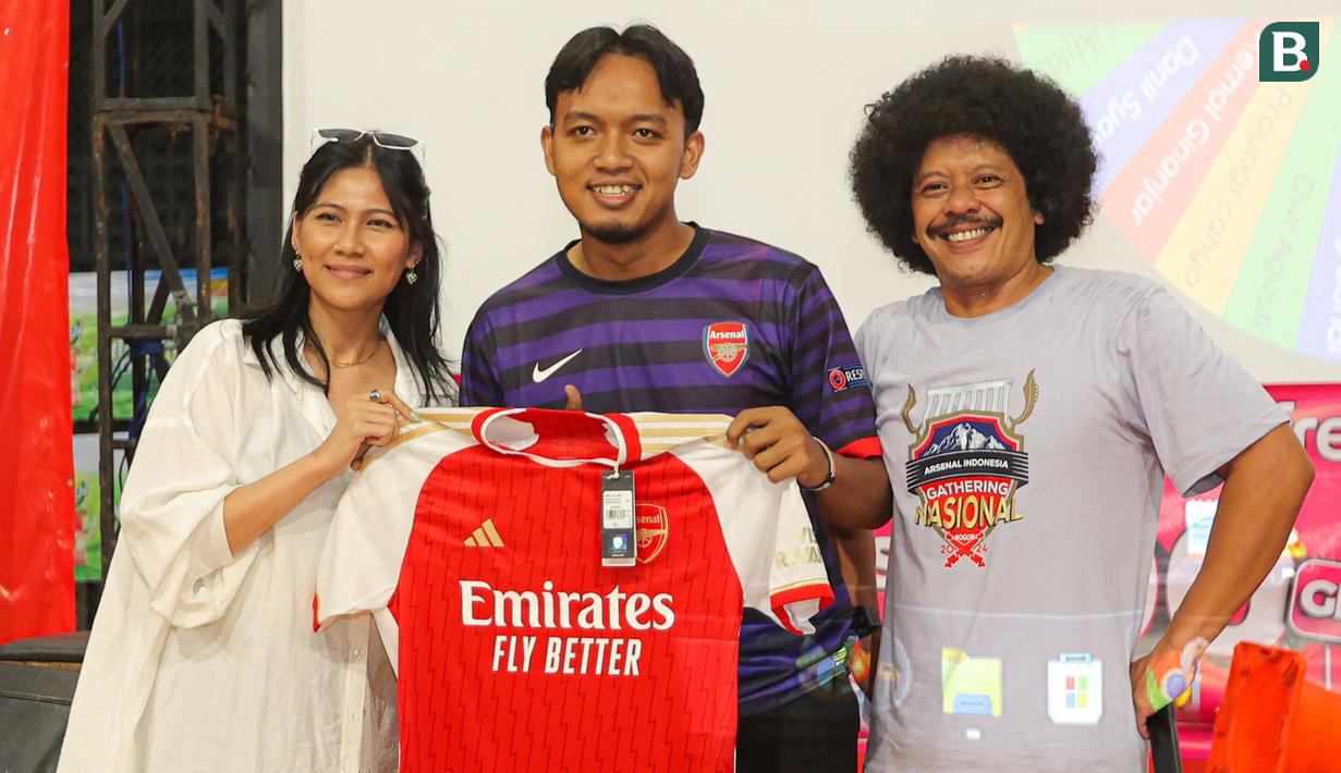 Salah seorang peserta Roaring Night pertandingan Liga Inggris 2023/2024 antara Arsenal kontra Crystal Palace yang beruntung mendapatkan merchandise berupa jersey original Arsenal berfoto bersama MC Eddi Brokoli dan pengurus Arsenal Indonesia Supporters (AIS) di Bucketlist Indonesia, Bogor, Sabtu (20/1/2024). (Bola.com/Bagaskara Lazuardi)