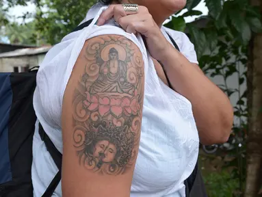 File foto pada 22 April 2014, Naomi Coleman asal Inggris memperlihatkan tato Sang Buddha di lengannya usai dideportasi dari Sri Lanka. Coleman yang sempat ditahan selama empat hari itu akhirnya mendapat uang ganti rugi. (Lakruwan WANNIARACHCHI/AFP)