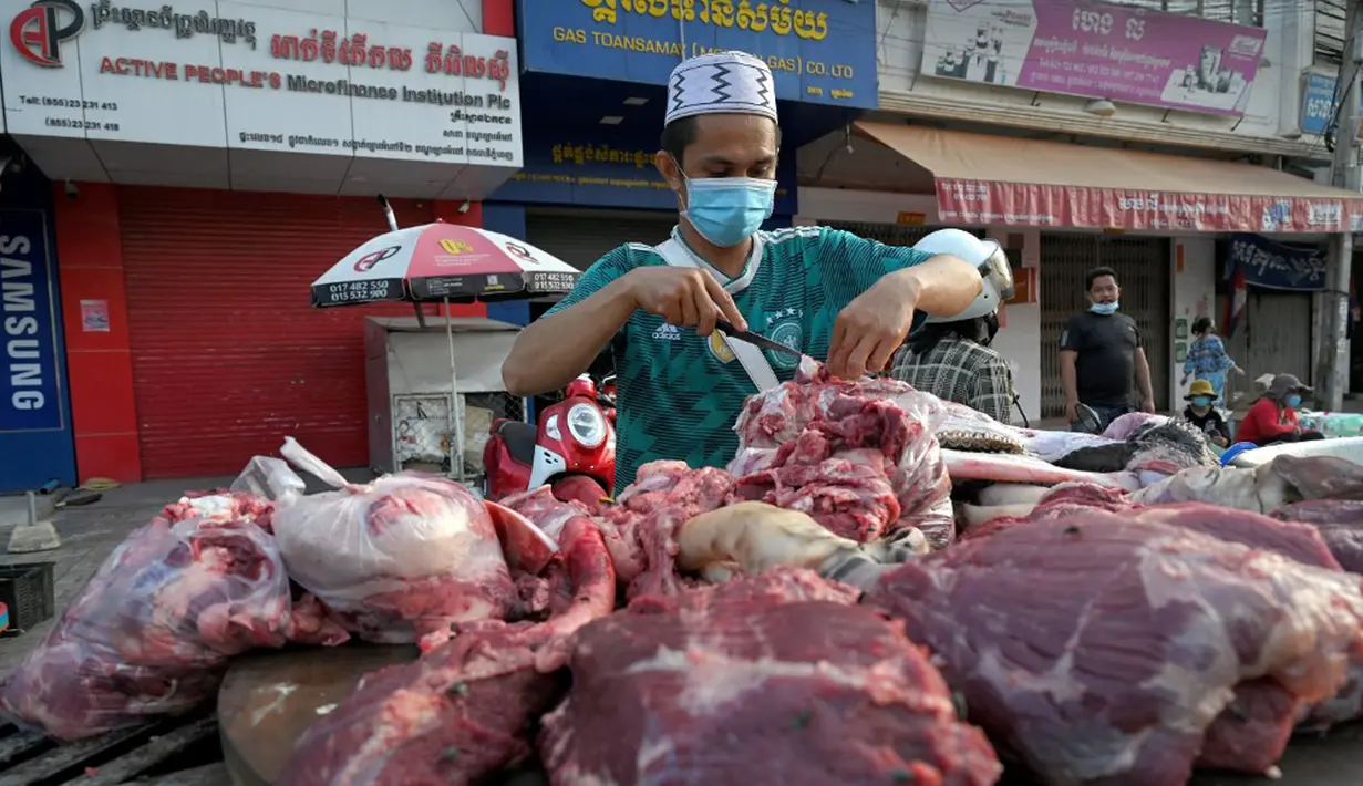 Seorang pedagang menyiapkan daging untuk dijual di sepanjang jalan karena pasar tetap tutup di tengah pembatasan lockdown yang diberlakukan untuk mencoba menghentikan lonjakan kasus virus corona COVID-19 di Phnom Penh, Kamboja, Selasa (11/5/2021). (TANG CHHIN Sothy/AFP)