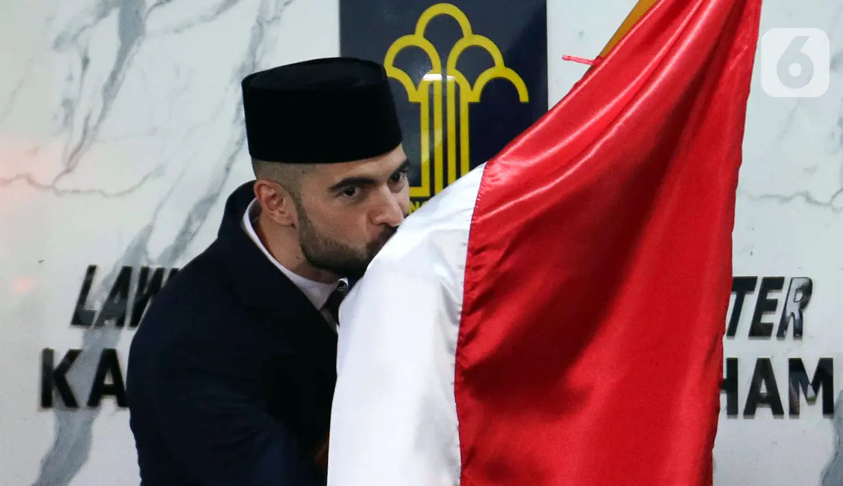 Pemain sepak bola Jordi Amat mencium bendera Merah Putih usai menjalani Sumpah Janji Setia Pewarganegaraan di Kantor Wilayah Kementerian Hukum dan HAM DKI Jakarta, Kamis (17/11/2022). Jordi Amat resmi menjadi Warga Negara Indonesia (WNI) setelah prosesi pengambilan sumpah yang digelar secara tertutup. (Liputan6.com/Herman Zakharia)