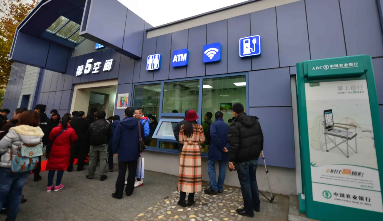 Warga mengantre di luar toilet umum pertama yang dilengkapi Wi-fi, mesin ATM hingga tempat pengisian energi untuk ponsel dan mobil listrik di Beijing, Kamis (19/11). Toilet ini juga akan dibuka di pinggiran kota Beijing dan kota lain.(CHINA OUT AFP PHOTO)