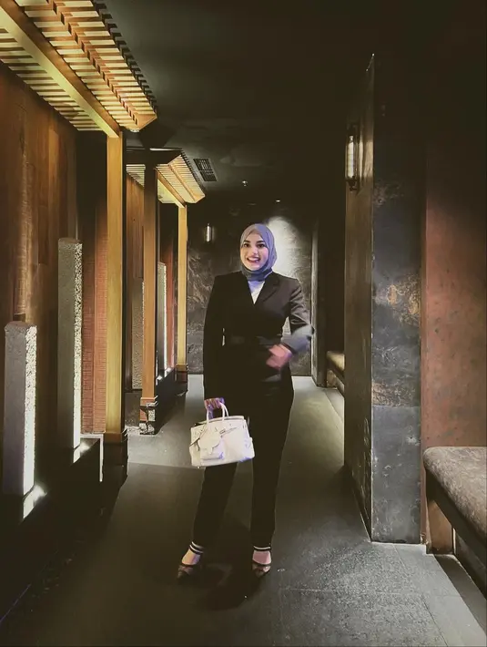 Aurel Hermansyah tampil dengan gaya lady boss, memadukan blazer dan celana panjang hitam, inner putih dan hijab ungu. Padu padan OOTDnya semakin sempurna saat ia menenteng tas Hermes berwarna putih. [Foto: Instagram/aurelie.hermansyah]