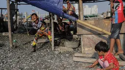 Anak-anak bermain sembari menemani ibunya mengupas kerang hijau di Kampung Nelayan Muara Angke, Jakarta, Rabu (3/7/2019). Dengan penghasilan rata-rata Rp 30 ribu/hari, para buruh pengupas kerang hijau tersebut harus cukup memenuhi kebutuhan hidup keluarganya. (Liputan6.com/Faizal Fanani)