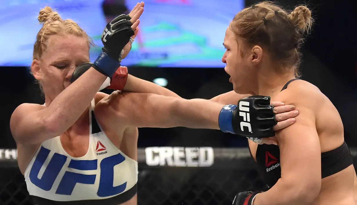 Pukulan dari Ronda Rousey, mendarat di wajah Holly Holm, pada pertarungan perebutan gelar juara kelas bantam UFC Women di Stadion Etihad, Melbourne, Minggu (15/11/2015). (AFP Photo/Paul Crock)
