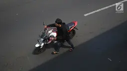 Pengendara mendorong motornya melintasi area Car Free Day Jalan Warung Jati Barat, Jakarta, Minggu (17/9).  Beberapa pengendara motor terlihat bebas menerabas jalan yang dipenuhi orang yang sedang berolahraga dan berjualan (Liputan6.com/Immanuel Antonius)