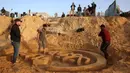 Selain ucapan Ramadan, Yazeed Abu Jarad sebelumnya juga dikenal karena membuat patung pasir angka "2026" di pantai Deir el-Balah pada akhir tahun 2025. Tampak dalam foto, warga membantu seniman Palestina, Yazeed Abu Jarad, saat ia membuat patung pasir dengan pesan ucapan "Selamat Datang, Ramadan" di sepanjang pantai di Khan Younis, selatan Gaza pada 17 Februari 2026. (Bashar Taleb/AFP)