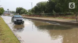 Sebuah mobil melintasi banjir rob di kawasan Pelabuhan Perikanan Samudera Nizam Zachman, Muara Baru, Jakarta, Sabtu (6/11/2021). Banjir rob tersebut disebabkan karena naiknya permukaan air laut. (Liputan6.com/Herman Zakharia)