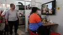 Warga menonton berita CCTV pagi di TV kunjungan pemimpin Korea Utara Kim Jong Un ke China, di sebuah restoran di daerah Jiexi di provinsi Guangdong China selatan, (28/3). Ini merupakan lawatan pertama Kim sejak menjabat pada 2011. (AP Photo/Andy Wong)