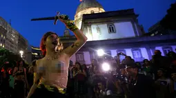 Seorang wanita dari sebuah kelompok seni bertelanjang dada saat berunjuk rasa memprotes maraknya pemerkosaan dan kekerasan seksual di pusat kota Rio de Janeiro, Brasil, Rabu (1/6). (REUTERS/Ricardo Moraes)