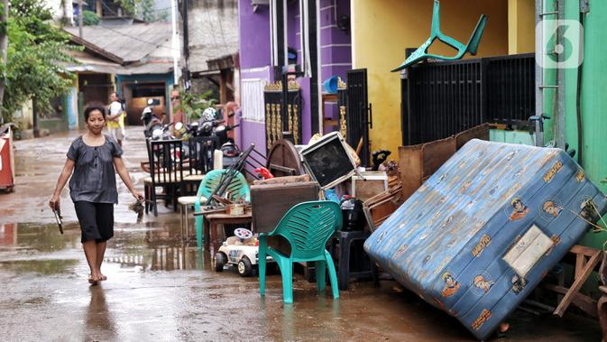Seorang perempuan melintasi barang-barang milik warga terdampak banjir di perumahan Ciledug Indah, Tangerang, Senin (22/2/2021). Banjir yang menggenangi perumahan itu membuat warga mengalami kerugian cukup besar karena barang-barang berharga mereka rusak parah. (Liputan6.com/Angga Yuniar)
