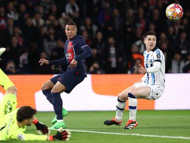 Pemain PSG, Kylian Mbappe (tengah) berusaha melepaskan tembakan meski ditepis oleh kiper Real Sociedad, Alex Remiro pada laga leg pertama 16 besar Liga Champions 2023/2024 di Parc des Princes, Paris, Prancis, Kamis (15/02/2024) WIB. (AFP/Franck Fife)