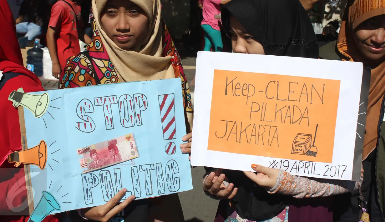 Mahasiswa yang tergabung dalam TPPJ KAMMI membawa poster saat aksi damai disela kegiatan Car Free Day di Jakarta, Minggu (9/4). Aksi itu sebagai bentuk imbauan agar masyarakat tidak terlibat politik uang dalam Pilkada DKI 2017. (Liputan6.com/Angga Yuniar)