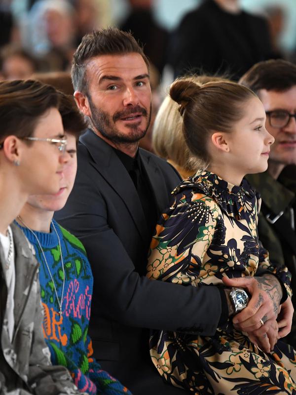 David Beckham bersama anak-anaknya Romeo Beckham, Cruz Beckham dan Harper saat menghadiri peragaan busana Musim Gugur/Musim Dingin 2020 Victoria Beckham dalam acara London Fashion Week di London, (16/2/2020). Beckham tampil dengan setelan jas hitam. (AFP/Daniel Leal-Olivas)