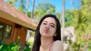 Berpose naik sepeda antik, DJ Una tampil cantik dalam balutan tank top pink fuschia dan high waist hijau rumput. (instagram.com @putriuna)